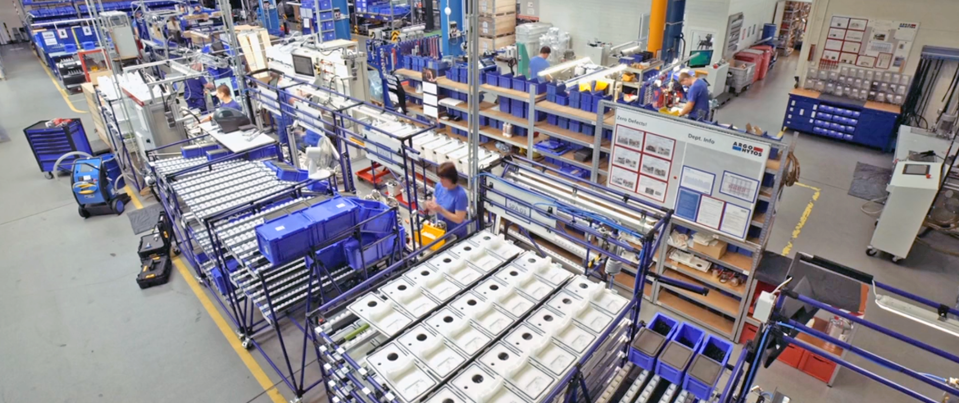 Industrial assembly and production line with workstations, conveyor systems, and material handling containers Industrial assembly and production line with workstations, conveyor systems, and material handling containers