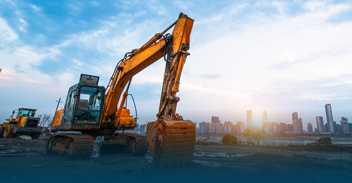 Hydraulikbagger im Einsatz auf einer Baustelle mit städtischer Skyline im Hintergrund