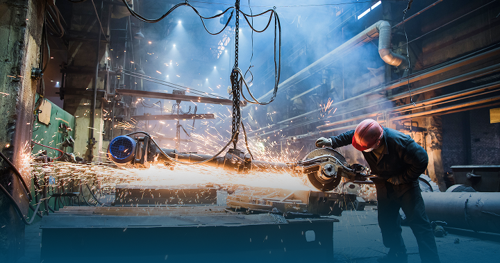 Fachkraft bei der Bearbeitung von Metall mit einer Trennmaschine in einer industriellen Fertigungsumgebung