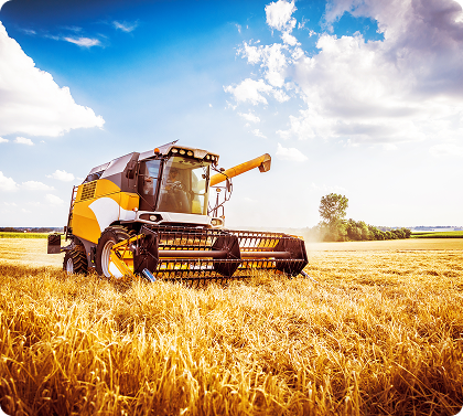 Combine harvester harvesting a grain field under a bright sky in an agricultural landscape