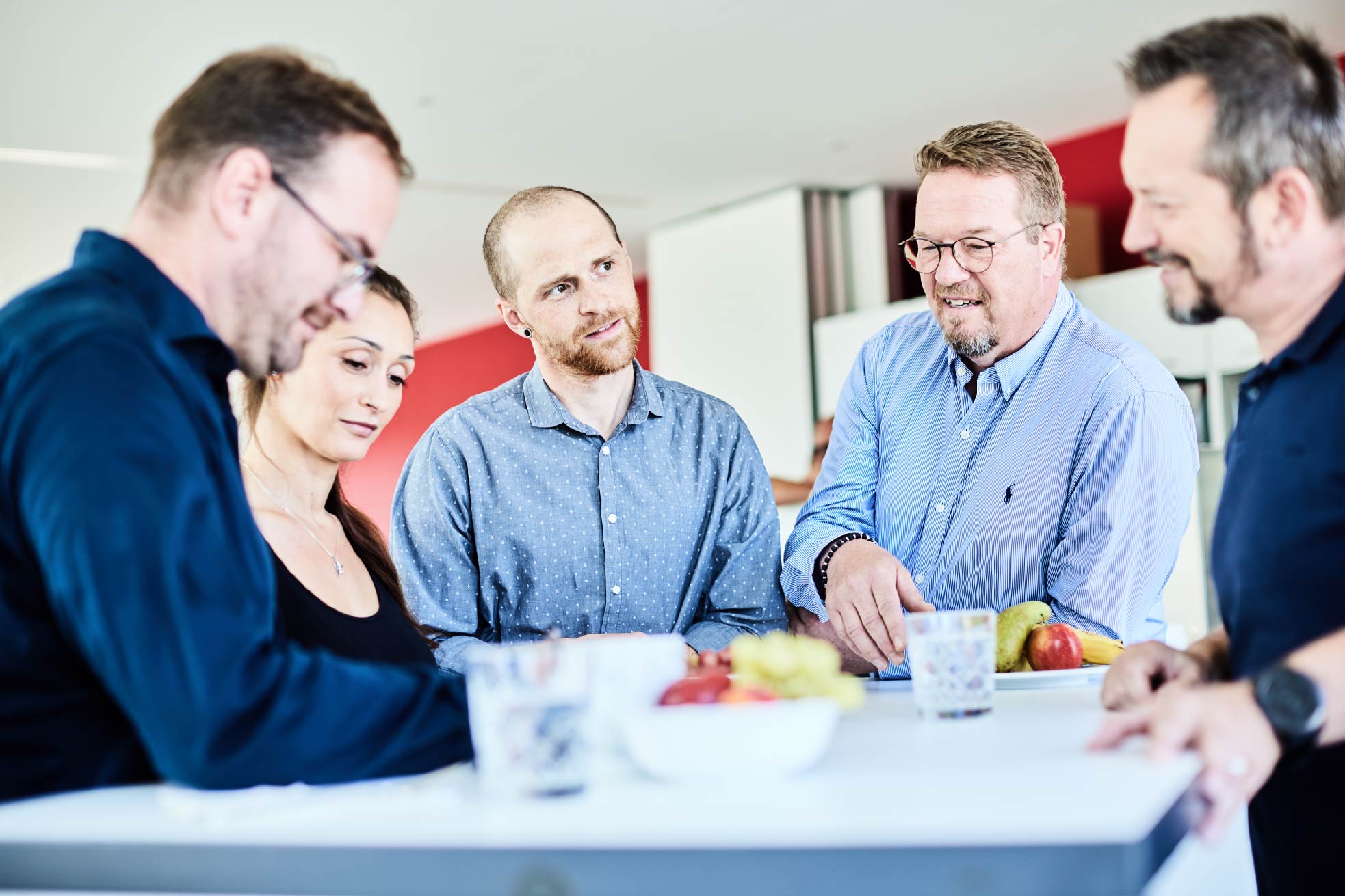 Mitarbeitende besprechen Unterlagen gemeinsam an einem Tisch in einem Besprechungsraum.