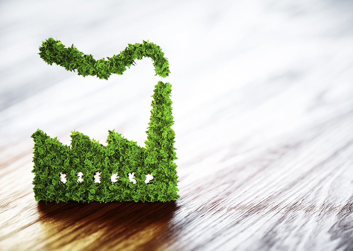 Green factory-shaped figure made of grass on a wooden surface, symbolizing sustainable manufacturing. Green factory-shaped figure made of grass on a wooden surface, symbolizing sustainable manufacturing.